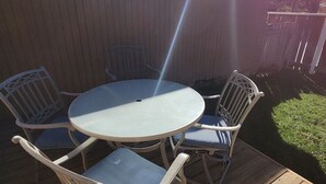 Um deck de madeira com uma mesa redonda e quatro cadeiras.