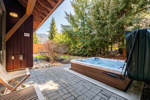 A hot tub in a wooden outdoor area with a wooden deck and a view of trees and mountains.