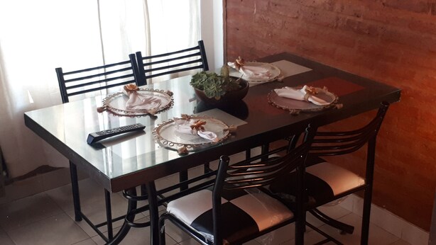 A dining table with four chairs, a remote control, and a potted plant.