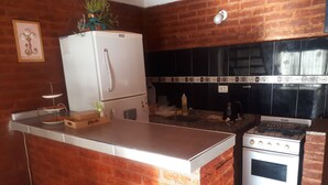 A kitchen with a brick wall, a white refrigerator, a stove, and a sink.