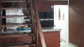 A wooden staircase leading to a second floor with a kitchen area visible in the background.