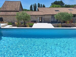 A swimming pool with a stone building in the background. - Gîte with Private Pool, Spa and Game Room (Cunèges)