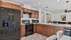A modern kitchen with wooden cabinets, a black refrigerator, a stove, and a microwave.