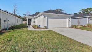 A single-story house with a garage, a front lawn, and a clear sky.