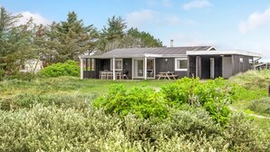 A modern, single-story house with a covered patio area, a dining table, and a barbecue grill. - Cozy home in Thisted with WiFi (Thisted)