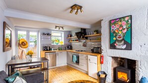 A modern kitchen with a central island, built-in oven, and a fireplace. - Cheerful Cottage in the Heart of Brighton (Brighton)