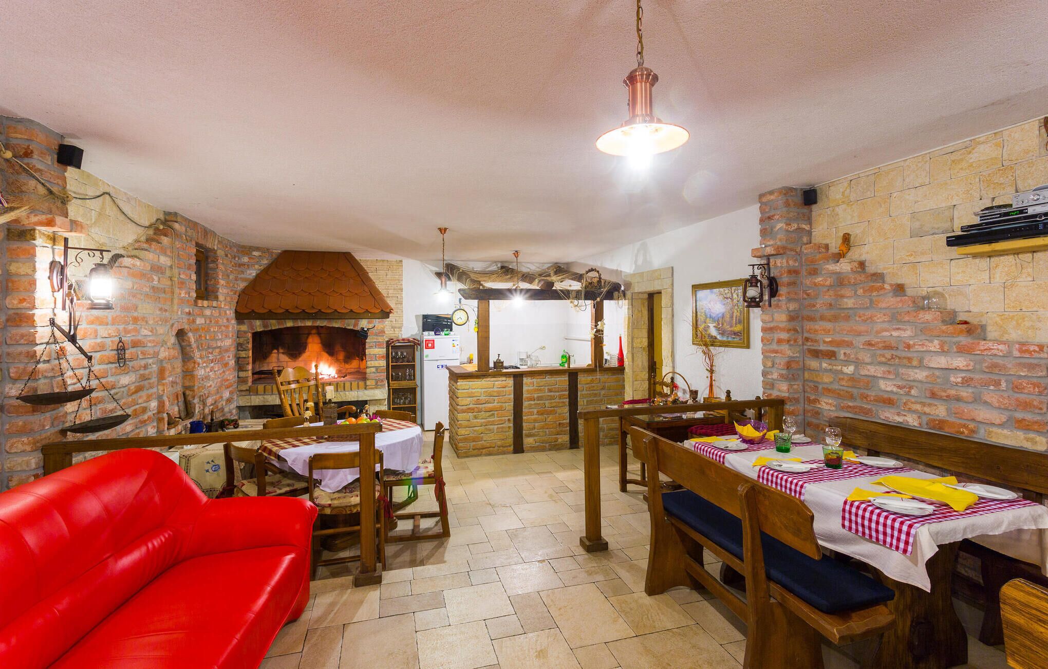 A cozy room with a brick fireplace, wooden furniture, and a red sofa.