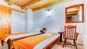 A room with two wooden beds, a wooden chair, a nightstand, a wall-mounted mirror, and a wall-mounted light fixture. - Stunning home in Starigrad with sauna (Starigrad)