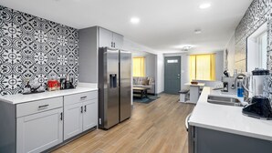 Cozinha moderna com ilha central, eletrodomésticos embutidos e painel de azulejos padronizado.