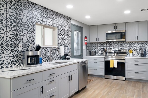 A modern kitchen with patterned backsplash, stainless steel appliances, and white cabinetry. - 30+ Days, Dog Friendly, Playground, Covered Parking, Hot Tub, Huge Yard. (Phoenix)