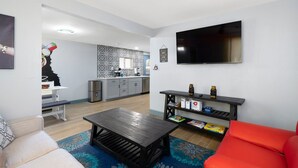 Uma sala de estar moderna com um sofá, uma mesa de centro e uma TV fixada na parede.