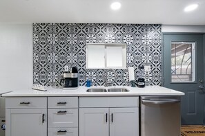 A compact kitchen with a white countertop, a double sink, a coffee maker, a blender, and a trash bin. - 30+ Days, Dog Friendly, Playground, Covered Parking, Hot Tub, Huge Yard. (Phoenix)