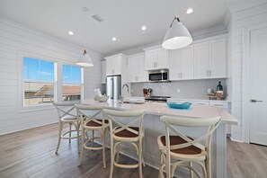Una cocina moderna con armarios blancos, una isla central y taburetes de bar.