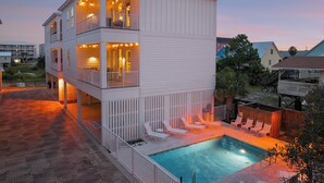 A two-story building with a balcony and a swimming pool. - 88° GAS Heated Pool, 85" TV, 3 King Beds, Steps to Beach, Arcade, Shuffleboard (Gulf Shores)