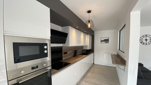 A modern kitchen with built-in appliances, a wooden countertop, and a pendant light. - Beautiful flat close to the city centre! (Quimper)