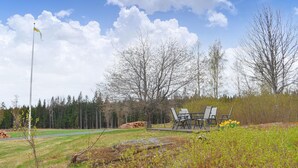 Un espace pique-nique équipé d’une table et de chaises, entouré d’arbres et d’un champ d’herbe.