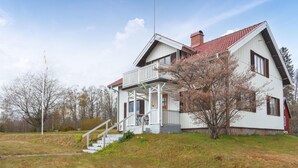 Une maison à deux étages avec un balcon, une cheminée et un drapeau.