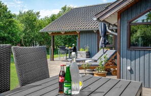 A wooden deck with outdoor furniture, including a table with bottles and a chair. - Amazing home in Fanø with sauna (Fanø)