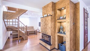 A modern living room with a wooden staircase, a built-in fireplace, and a cozy seating area.