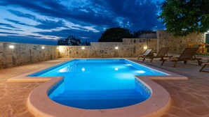 A swimming pool with a stone wall and lounge chairs. - Pet friendly home in Benkovac (Benkovac)