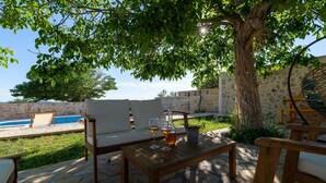 An outdoor seating area with a pool, stone flooring, and a tree providing shade. - Pet friendly home in Benkovac (Benkovac)