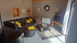 Ein modernes Wohnzimmer mit einem schwarzen Ledersofa, einem Fernseher und einer Uhr an der Wand.