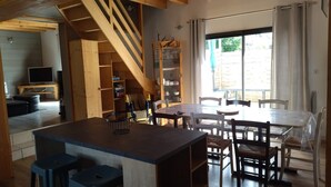 Eine gemütliche Küche mit einer Holztreppe, einem Essbereich mit Tisch und Stühlen und einem Fernseher in der Ecke.