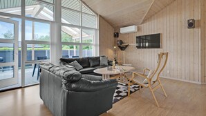 Een moderne woonkamer met een leren modulaire bank, een ronde salontafel en een tv aan de muur.