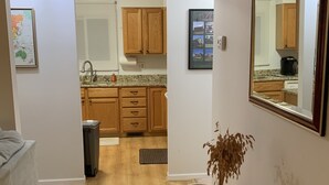 A hallway leading to a kitchen with wooden cabinets, a sink, and a framed picture on the wall. - Bay view from Calvert Cliffs, Solomons Island & State Park nearby (Lusby)