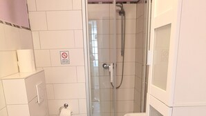 A bathroom with a toilet, bidet, shower, and a trash can. - Vacation apartment in a beautiful location between 2 lakes for 2-6 people (Malente)
