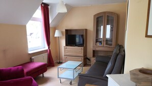 A living room with a sofa, a small table, a TV, and a cabinet. - Vacation apartment in a beautiful location between 2 lakes for 2-6 people (Malente)