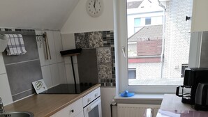 A modern kitchen with white cabinets, a pink refrigerator, and a window with a view of buildings. - Vacation apartment in a beautiful location between 2 lakes for 2-6 people (Malente)