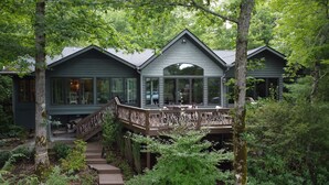 Une cabane dotée d’une terrasse et d’un escalier, le tout entouré d’une forêt dense.