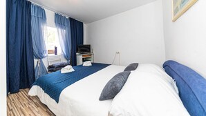 Un dormitorio con cama, un escritorio con televisor y una ventana con cortinas.