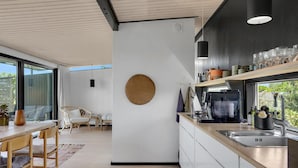 Een moderne keuken met een groot raam, een rond geweven wandobject en een koffieapparaat.