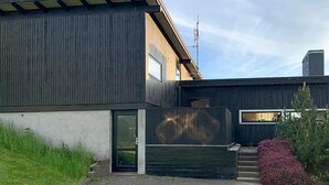 Een modern huis met twee verdiepingen, een donkere buitenkant, een zichtbare schotelantenne en een garage.