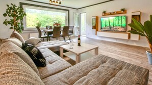 A modern living room with a sofa, coffee table, and a TV mounted on the wall. - Nice apartment in Marienmünster (Marienmünster)