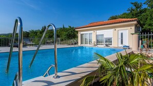 A swimming pool with metal ladders, a covered patio area, and a building with a red-tiled roof. - Gorgeous home in Jadranovo (Jadranovo)