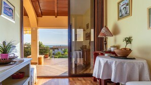A room with a wooden ceiling, a glass door leading to a balcony, a table with a white tablecloth, and a lamp. - Gorgeous home in Jadranovo (Jadranovo)