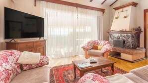 A living room with a flat-screen TV, floral sofas, a coffee table, and a fireplace. - Gorgeous home in Jadranovo (Jadranovo)