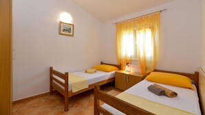 A small, clean room with two single beds, a wooden wardrobe, a bedside table with a lamp, and a framed picture on the wall. - Awesome apartment in Starigrad Paklenica (Starigrad Paklenica)