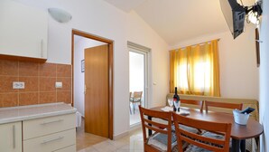 A compact kitchen with a dining area, a wooden door, and a window with curtains. - Awesome apartment in Starigrad Paklenica (Starigrad Paklenica)