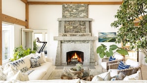 A cozy living room with a stone fireplace, comfortable seating, and a large plant. - Private Hilltop Chilmark Estate with private tennis court, gym and hot tub (Chilmark)