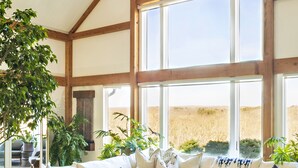 A spacious living area with a large sectional sofa, wicker chairs, and a coffee table. - Private Hilltop Chilmark Estate with private tennis court, gym and hot tub (Chilmark)