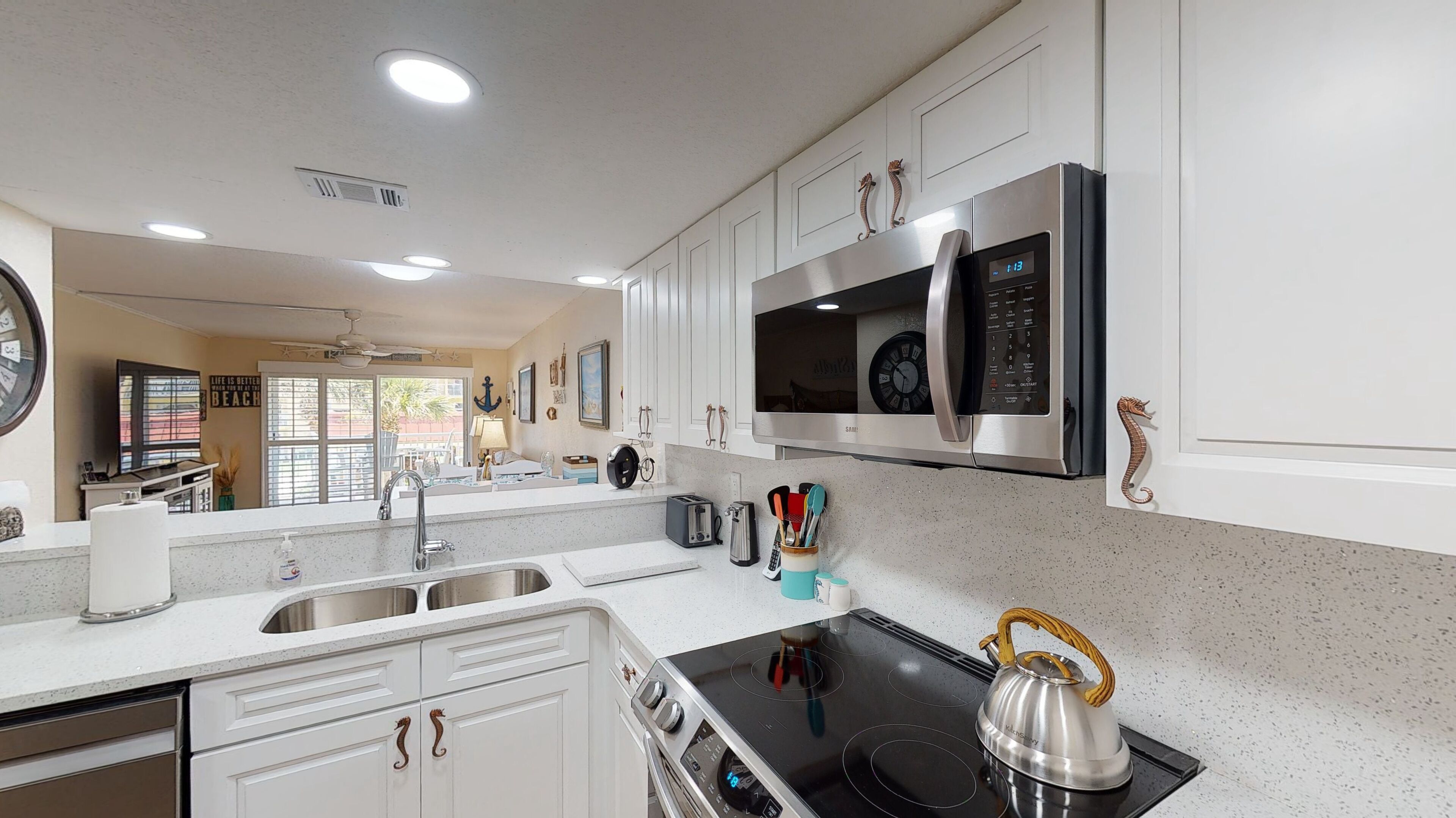 A modern kitchen with white cabinetry, stainless steel appliances, and a black induction cooktop.