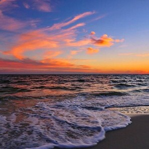 Een strand met golven en een zonsondergang.