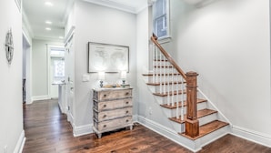 Una escalera con escalones de madera y barandillas blancas que conduce a un piso superior.