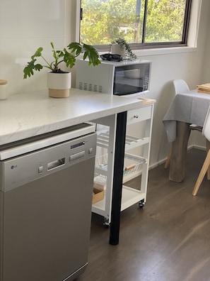 Compact kitchen with dishwasher, microwave oven, and ample storage.
