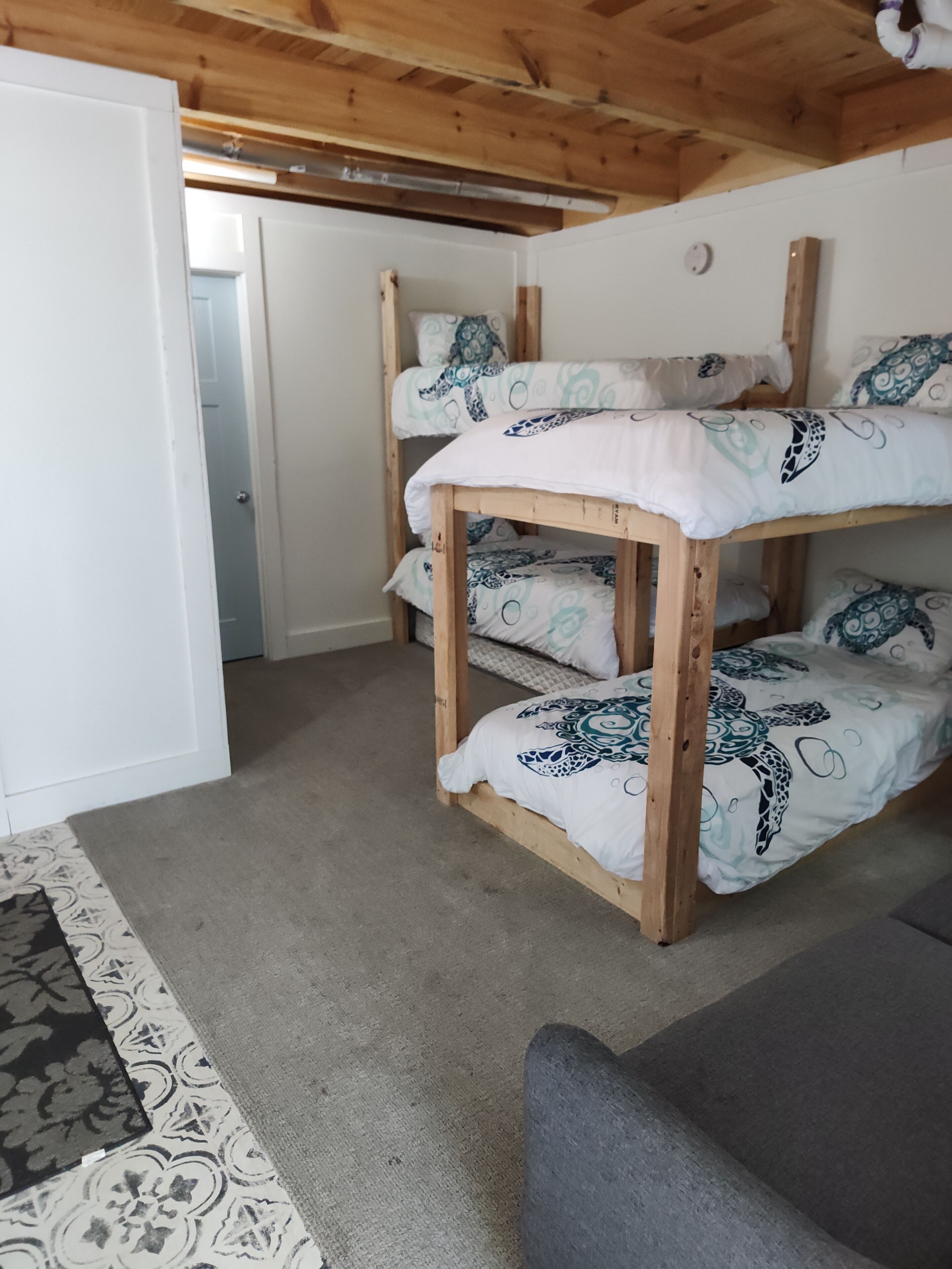A bunk bed with patterned bedding, a wooden ceiling, and a carpeted floor.