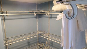 Un cuarto de almacenaje con estanterías metálicas, un perchero blanco y una pared azul.